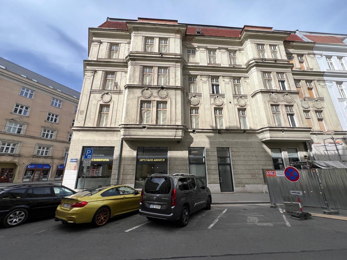 Fasáda rohového domu před obnovou — zašedlá omítka a poškozené římsy
